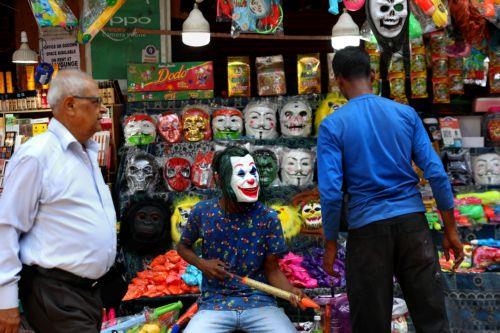 epa10500093 A vendor wears a Joker mask as he sells party items and colored powders ahead of the Holi celebrations in Kolkata, India, 03 March 2023. Holi, also known as the Festival Of Colors, is an ancient Indian Hindu festival symbolizing the victory of good over evil and marking the arrival of spring. It is held annually with joyful gatherings during...