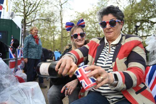 epa10610416 Royal fans pour fizzy wine as they wait on the coronation procession route on The Mall in London, Britain, 05 May 2023. Britain's King Charles III's coronation takes place at Westminster Abbey in London on 06 May 2023.  EPA/NEIL HALL