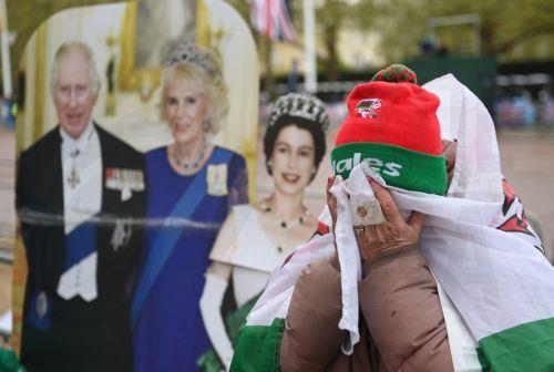 epa10610426 A royal fan cries as her card board cut-outs are rained on as people wait on the coronation procession route on The Mall in London, Britain, 05 May 2023. Britain's King Charles III's coronation takes place at Westminster Abbey in London on 06 May 2023.  EPA/NEIL HALL