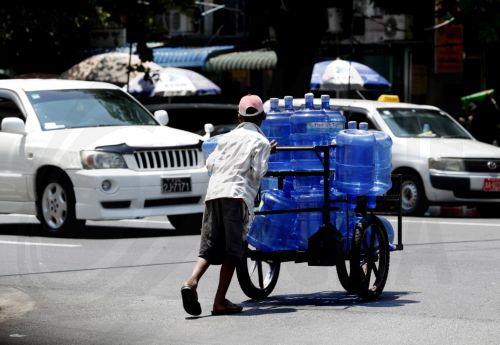epa10614931 A man pushes a cart full of drinking water bottles on the street in Yangon, Myanmar, 08 May 2023. Myanmar and some other South East-Asia countries have been affected by high temperatures in April and May.  EPA/NYEIN CHAN NAING
