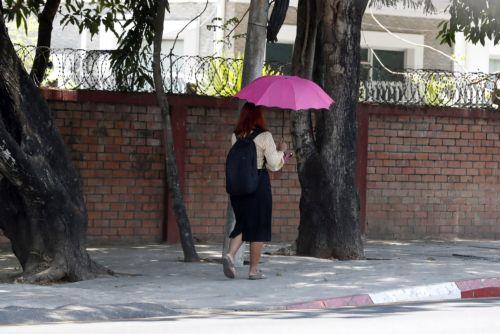 epa10614933 A woman uses an umbrella as she walks on the street in Yangon, Myanmar, 08 May 2023. Myanmar and some other South East-Asia countries have been affected by high temperatures in April and May.  EPA/NYEIN CHAN NAING