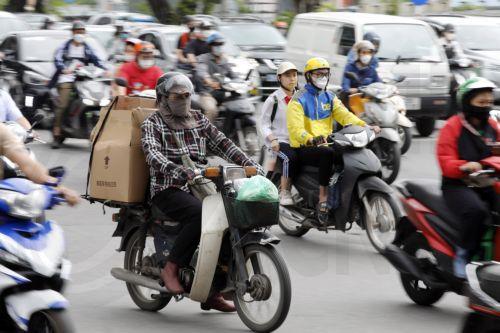 epa10614936 People wear long clothing to protect themselves from the heat while riding motorcycles along a street in Hanoi, Vietnam 08 May 2023. Vietnam reported a record-high temperature of 44.2 degrees Celsius on 07 May 2023, according to a forecast from the National Center for Hydrometeorological Forecasting.  EPA/LUONG THAI LINH