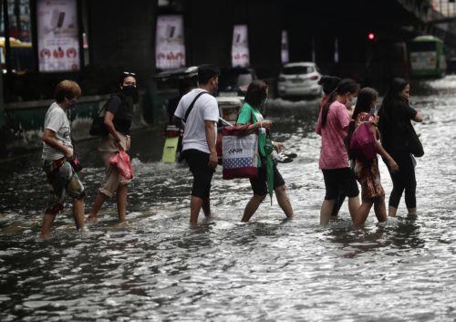 epa10830559 Filipinos wade through a flooded street in Manila, Philippines, 31 August 2023. Typhoon Saola, which has left the Philippine Area of Responsibility, and Tropical Storm Haikui off the coast of extreme northern provinces are enhancing a southwest monsoon bringing rains in the western Luzon region of the country, according to data from the...