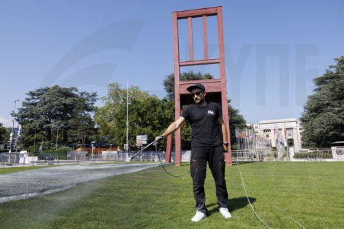 epa10855746 French-Swiss artist Saype works on his giant biodegradable landart painting entitled 'All of us' around the Broken Chair on the Place des Nations in front of the European headquarters of the United Nations, in Geneva, Switzerland, 08 September 2023 (issued 12 September 2023). Handicap International has invited the artist Saype to realize a giant...