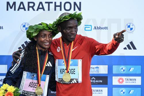 epa10880256 Womenâ€™s winner Tigst Assefa of Ethiopia (L) and Menâ€™s winner Eliud Kipchoge of Kenya (R) celebrate during the flower ceremony of the Berlin Marathon 2023, in Berlin, Germany, 24 September 2023. Assefa set a new women's world record of 2:11:53.  EPA/Filip Singer