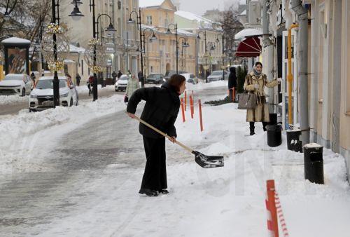 epa10997698 A woman shovels snow on a snow covered street in Moscow, Russia, 27 November 2023. Moscow has come under a heavy snowfall, anticipated to persist till the end of the week, as meteorologists report. Moscow authorities have issued advisories for residents to tread carefully while commuting, as snowfall could lead to increased disruptions and the...