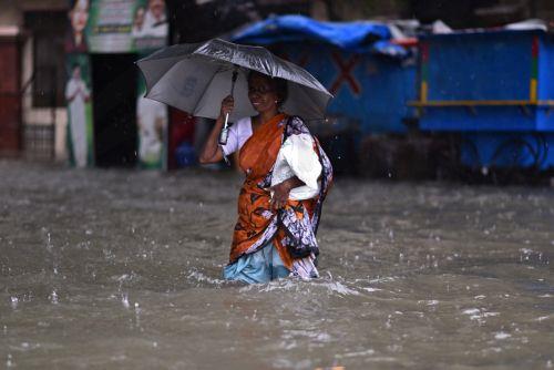 epa11010543 A woman wades through a flooded road during heavy rains as Cyclone Michaug is expected to make landfall on the eastern Indian coast, in Chennai, India, 04 December 2023. The Indian Meteorological Department has issued a red alert for heavy rains in Chennai as the cyclonic storm, 'Cyclone Michaung' is anticipated to make landfall between Andhra...