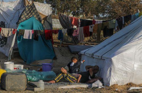 epa11317096 A displaced Palestinian man who fled with his family from the northern Gaza strip plays with his son outside their shelter at Deir Al Balah beach in the southern Gaza Strip, 03 May 2024. More than 34,550 Palestinians and over 1,455 Israelis have been killed, according to the Palestinian Health Ministry and the Israel Defense Forces (IDF), since...