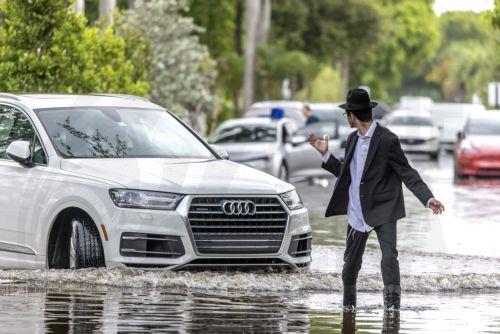 epa11408205 A person walks through a flooded neighborhood in Hallandale Beach, Florida, USA, 13 June 2024. Heavy rains triggered a flash flood and the Broward and Miami-Dade counties saw record rainfall amounts in a matter of hours, ranging from 15 inches to 26 inches, the National Weather Service said.  EPA/CRISTOBAL HERRERA-ULASHKEVICH