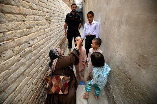 epa11594237 A police officer looks on as a health worker administers polio vaccine drops to a child during a door-to-door vaccination campaign, in Peshawar, Pakistan, 09 September 2024. A case of poliovirus has emerged in Islamabad after 16 years, marking the total number of cases in Pakistan this year at 17. The eight-year-old boy, from Union Council Rural...
