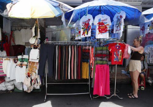 epa11672549 A foreign tourist buys clothes at a market in Bangkok, Thailand, 21 October 2024. Deputy Finance Minister Julapun Amornvivat said Thailand's economy has the potential to grow 3 percent in 2024, revised up from 2.7 percent of earlier projections, and will expand more in 2025, driven by the government's stimulus measures with temporarily...