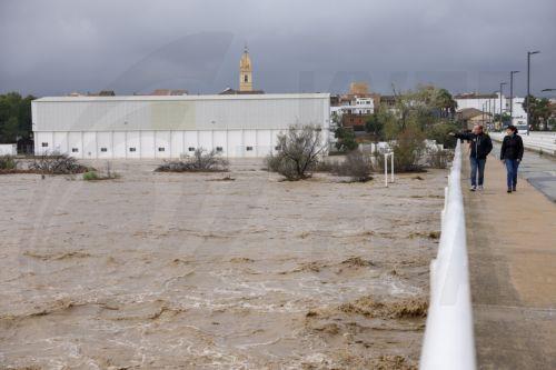 epa11690550 People look the flow of the Magre river, in Alfarp, Valencia, Spain, 29 October 2024. The State Meteorological Agency (AEMET) has activated red alerts for rain in various areas of the province of Valencia due to heavy rainfall caused by the storm DANA that is hitting several areas of Spain.  EPA/ANA ESCOBAR