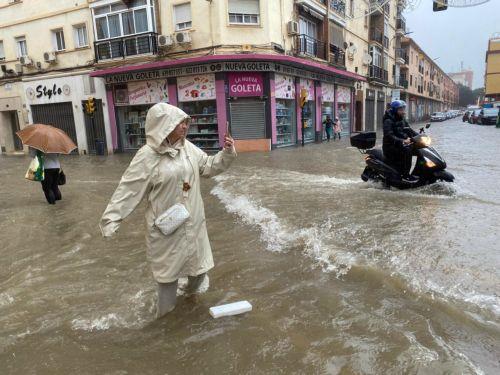 epaselect epa11718613 A woman takes a photo of a flooded street in Malaga, Andalusia, Spain, 13 November 2024. Water and hail storms in Malaga have resulted in flooding and the formation of enormous pools of water on some of the city's main streets. Malaga is on red alert for extreme risk owing to the expected heavy rainfall.  EPA/MARIA ALONSO