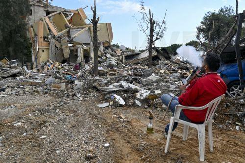epa11745409 A man smokes a waterpipe in front of a damaged building, as displaced residents return to Nabatieh following a ceasefire deal between Israel and Hezbollah, in southern Lebanon, 28 November 2024. The 60-day ceasefire came into force on 27 November.  EPA/WAEL HAMZEH