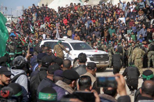 epa11851288 A vehicle of the International Committee of the Red Cross (ICRC) drives in front of Palestinians and Hamas militants gathered in the center of Gaza City ahead of the release of four Israeli hostages in the Gaza Strip, 25 January 2025. The four Israeli hostage soldiers Liri Albag, Naama Levy, Karina Ariev, and Daniella Gilboa, were taken hostage...
