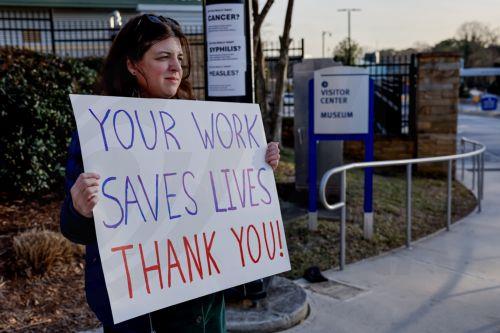 epa11906308 A protestor greets employees with support as they leave work at the US Centers for Disease Control and Prevention (CDC) headquarters in Atlanta, Georgia, USA, 18 February 2025. The Trump administration has announced job cuts of nearly 1,300 probationary employees at the CDC, equal to about one-tenth of the agency's workforce.  EPA/ERIK S. LESSER