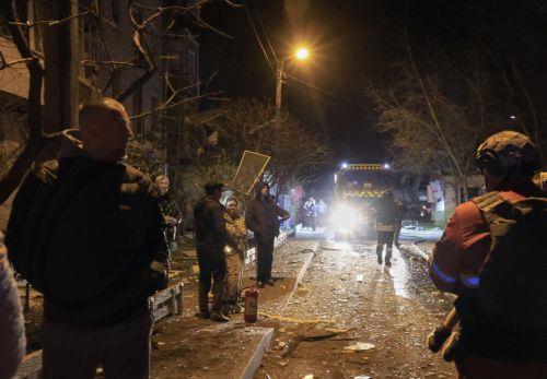 epa12008771 Locals stand outside a damaged residential building at the site of a drone attack in Kharkiv, Ukraine, late 03 April 2025 (issued 04 April 2025), amid the ongoing Russian invasion. At least four people died and 35 other people were injured, including one child, according to the State Emergency Service.  EPA/SERGEY KOZLOV