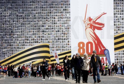 epa12069327 People walk on the Dvortsovaya (Palace) Square decorated with a panel depicting images of Russian veterans, ahead of the Victory Day celebrations in St. Petersburg, Russia, 02 May 2025. Russia will mark on 09 May the 80th anniversary of the victory of the Soviet Union over Nazi Germany and its allies in World War II.  EPA/ANATOLY MALTSEV