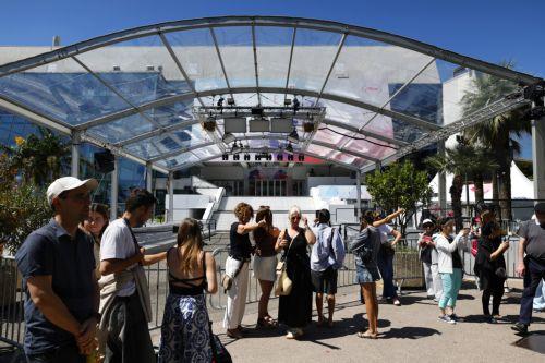 epa12093742 People stand in front of the Palais des Festivals ahead of the 78th annual Cannes Film Festival in Cannes, France, 12 May 2025. The film festival runs from 13 to 24 May 2025.  EPA/GUILLAUME HORCAJUELO