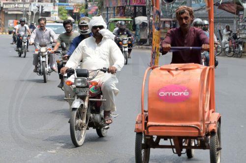 epa12130192 Commuters ride motorbikes along a road on a day of scorching heat, in Lahore, Pakistan, 24 May 2025. Pakistan's Punjab province and its capital Lahore are experiencing an intense heatwave with temperatures climbing over 40 degrees Celsius.  EPA/RAHAT DAR