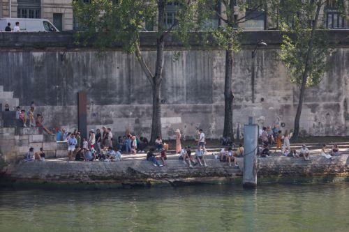 epa12189696 People sit at the bank of Seine river during a heatwave in Paris, France, 21 June 2025. According to forecasts, France experiences high temperatures across the country.  EPA/MOHAMMED BADRA