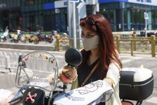epa12192057 A woman rides a scooter along a street during hot weather in Beijing, China, 23 June 2025. The city issued an orange alert for high temperatures as the mercury was expected to reach 38 degrees Celsius within 24 hours, according to the Beijing Meteorological Observatory.  EPA/WU HAO