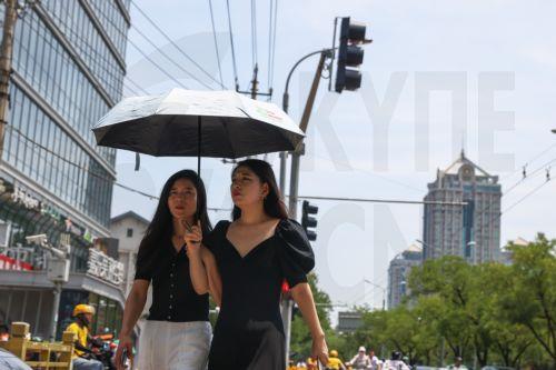 epa12192064 People walk on a street during hot weather in Beijing, China, 23 June 2025. The city issued an orange alert for high temperatures as the mercury was expected to reach 38 degrees Celsius within 24 hours, according to the Beijing Meteorological Observatory.  EPA/WU HAO