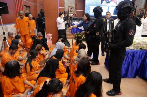 epa12192129 Indonesian police officers hold their rifles in front of alleged drug dealers during a press conference on the disclosure of a drug distribution network at the Directorate General of Customs and Excise office in Jakarta, Indonesia, 23 June 2025. The Indonesian National Narcotic Agency, together with Indonesian Customs, have succeeded in...