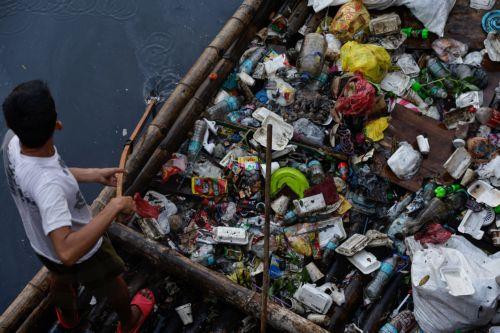epa12216974 A villager on a bamboo raft collects trash along a creek in Manila, Philippines 05 July 2025. The mayor of Manila ordered intensified waste collection and cleanup operations of waterways, canals and populated areas beginning 05 July, after declaring a health emergency on just his first week as newly-elected city head.  EPA/ROLEX DELA PENA