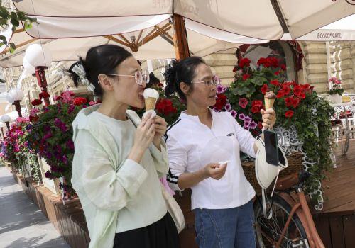 epa12232115 Tourists eat ice cream as they visit the Red Square during a hot summer day, in Moscow, Russia, 11 July 2025. Temperatures in the Moscow region reached more than 36 degrees Celsius.  EPA/SERGEI ILNITSKY