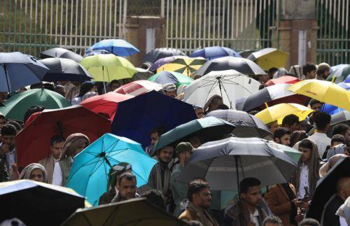 epa12245998 People hold umbrellas to shield themselves from the sun amid hot weather in Sana'a, Yemen, 18 July 2025. Yemen's national meteorological service warned about hot weather with temperatures ranging between 32 and 43 degrees Celsius across most parts of the Arab country.  EPA/YAHYA ARHAB