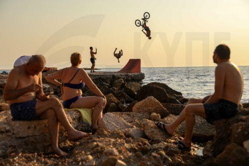 epaselect epa12248114 A BMX rider dives into the water after riding his bike over a ramp that was set up by the sea, during a heatwave at Kavouri beach, near Athens, Greece, 19 July 2025.  EPA/GEORGE VITSARAS