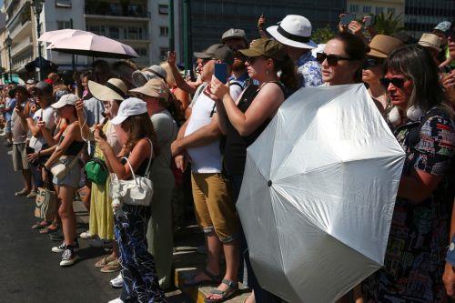 epa12249117 Tourists wear hats and  use fans and umbrellas as they stroll in the city center during a heatwave, in Athens, Greece, 20 July 2025. An intense heatwave with temperatures exceeding 44 degrees Celsius in some locations is expected in Greece and parts of the Balkans from Monday 21 July, according to a forecast issued by the National Observatory of...