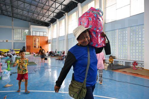 epa12258152 Evacuees carry their belongings at a Thai government evacuation center after being relocated amid clashes between Thai and Cambodian soldiers along the disputed border in Prasat district, Surin province, Thailand, on 24 July 2025. According to the Ministry of Public Health, at least 12 people were killed and 35 injured after armed clashes...