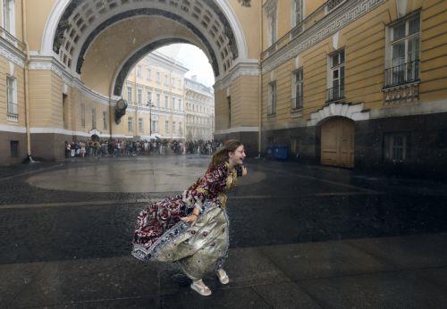 epa12275135 A street actor dressed in a period costume reacts to heavy rain under the General Staff Arch on Palace Square in central St. Petersburg, Russia, 31 July 2025.  EPA/ANATOLY MALTSEV