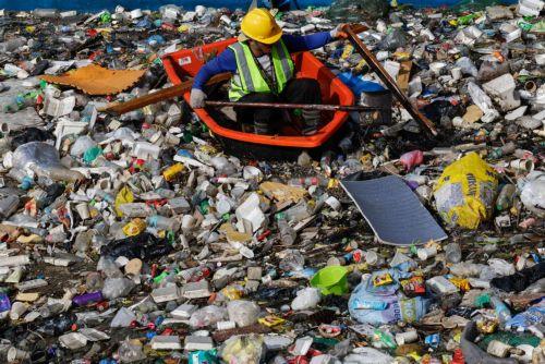 epa12311486 A worker from city environment and sanitation services uses a raft to navigate a creek with accumulated trash and debris during a clean-up operation at the boundary of San Juan and Quezon City, Metro Manila, Philippines, 20 August 2025. Almost two consecutive weeks of typhoon and heavy monsoon rains in the month of July triggered massive...