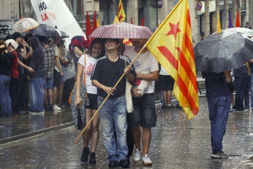 epa12369454 People with the Catalonian National flag try to shelter from the rain during the Catalonian National Day (Diada) in Barcelona, Spain on 11 September 2025. The Catalonian national day is the anniversary of the fall of Barcelona during the Succession War in 1714.  EPA/QUIQUE GARCIA