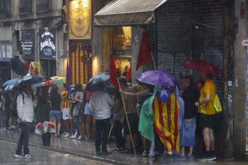 epa12369453 People with the Catalonian National flag try to shelter from the rain during the Catalonian National Day (Diada) in Barcelona, Spain on 11 September 2025. The Catalonian national day is the anniversary of the fall of Barcelona during the Succession War in 1714.  EPA/QUIQUE GARCIA
