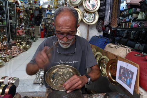 epa12402159 A Tunisian craftsman carves patterns on a copper plate in the Old City market of Tunis, Tunisia, 24 September 2025. Tunisia's gross domestic product (GDP) expanded by 3.2 percent in the second quarter of 2025, according to estimates from the National Institute of Statistics (INS).  EPA/MOHAMED MESSARA