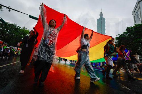 epaselect epa12480487 People carry a giant rainbow flag and accessories during the annual Taiwan Pride parade in Taipei, Taiwan, 25 october 2025. This year's theme, 'Beyond Links: More Than Clicks', examines online conversations about gender and the challenges LGBTQ+ individuals face in the digital age.  EPA/RITCHIE B. TONGO