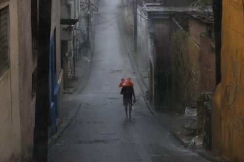epa12488825 A person protects themselves from the rain in Santiago de Cuba, Cuba, 28 October 2025. Cuba's Institute of Meteorology (Insmet) predicts that Melissa will hit the eastern tip of the island as an “extremely dangerous” hurricane, probably a category 4 (out of 5) on the Saffir-Simpson scale.  EPA/Ernesto Mastrascusa
