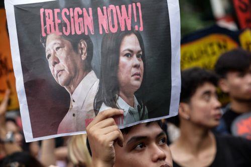 epa12539493 A protester holds a sign calling for the resignation of Philippine President Ferdinand Marcos Jr. and Vice-President Sara Duterte during an anti-corruption rally by predominantly college-level students in Manila, Philippines, 21 November 2025. President Marcos on 21 November announced that arrest warrants have been issued for a former...
