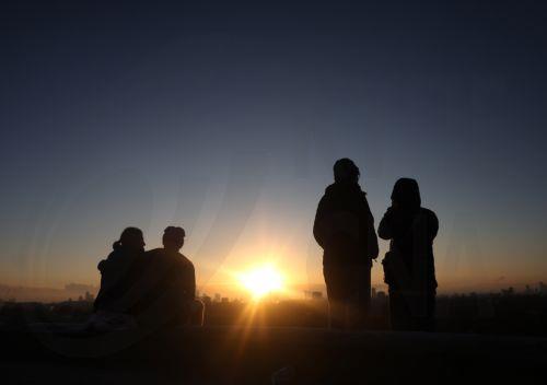 epa12539678 People watch as the sun rises over Primrose Hill in London, Britain, 21 November 2025. Winter weather continues across the UK, with temperatures falling below zero overnight. The Met Office has described the conditions as the 'first notable cold snap of this autumn,' bringing 'wintry hazards' and prompting the agency to issue warnings for snow...
