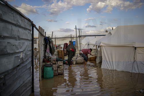 epa12548241 An internally displaced Palestinian family stands in a puddle next to their tent on a rainy day in Al Zaitun neighbourhood in the east of Gaza City, Gaza Strip, 25 November 2025. Around 1.9 million people in Gaza, nearly 90 percent of the population, have been displaced since the Israel-Hamas conflict began in October 2023, according to the UN. ...