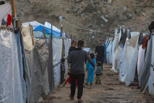 epa12548244 An internally displaced Palestinian father carries his daughter between tents on a rainy day in Al Zaitun neighbourhood in the east of Gaza City, Gaza Strip, 25 November 2025. Around 1.9 million people in Gaza, nearly 90 percent of the population, have been displaced since the Israel-Hamas conflict began in October 2023, according to the UN. ...