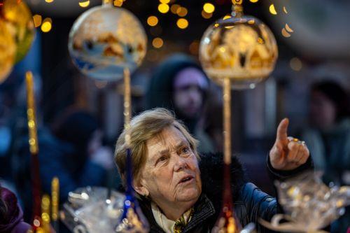 epa12562770 A visitor looks at Christmas decorations at the market in Old Town Square, Prague, Czech Republic, 01 December 2025. Christmas markets, traditionally selling mulled wine, roasted chestnuts, hot mead, chimney cakes, and Christmas decorations and gifts, opened across the Czech Republic during the first Advent weekend.  EPA/MARTIN DIVISEK