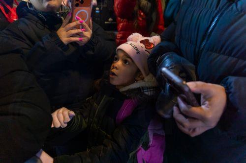 epa12573436 A child looks up at the stage during the annual Christmas tree lighting at Lou Gehrig Plaza in the Bronx borough of New York, New York, USA, 05 December 2025.  EPA/MADISON STEWART