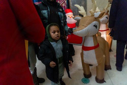 epa12573450 A child waits beside holiday decorations inside Bronx Borough Hall during the annual Christmas tree lighting at Lou Gehrig Plaza in the Bronx borough of New York, New York, USA, 05 December 2025.  EPA/MADISON STEWART