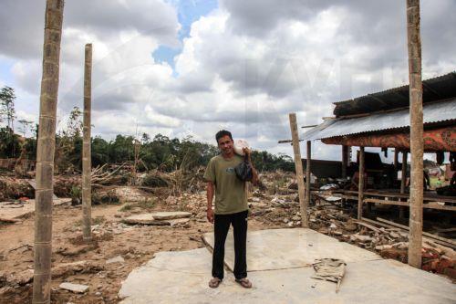 epa12578282 A man carrying his belongings, stands on a damaged house at a flood affected area in Aceh Tamiang, Aceh province, Indonesia, 08 December 2025. According to the National Disaster Management Agency, floods and landslides triggered by Tropical Cyclone Senyar have killed 961 people across the provinces of Aceh, North Sumatra, and West Sumatra, while...