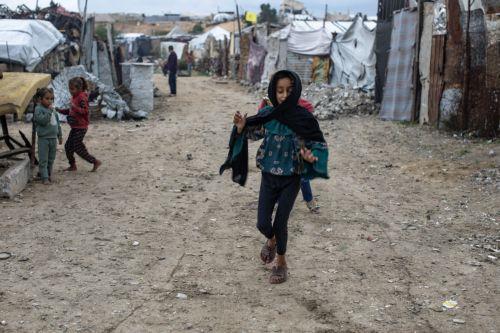 epa12594406 Displaced Palestinian children play in front of their tents on a rainy day in the city of Khan Younis, in the southern Gaza Strip, 15 December, 2025.  According to the UN around 90 percent of the population or 1.9 million people in Gaza have been displaced since the start of the conflict.  EPA/HAITHAM IMAD